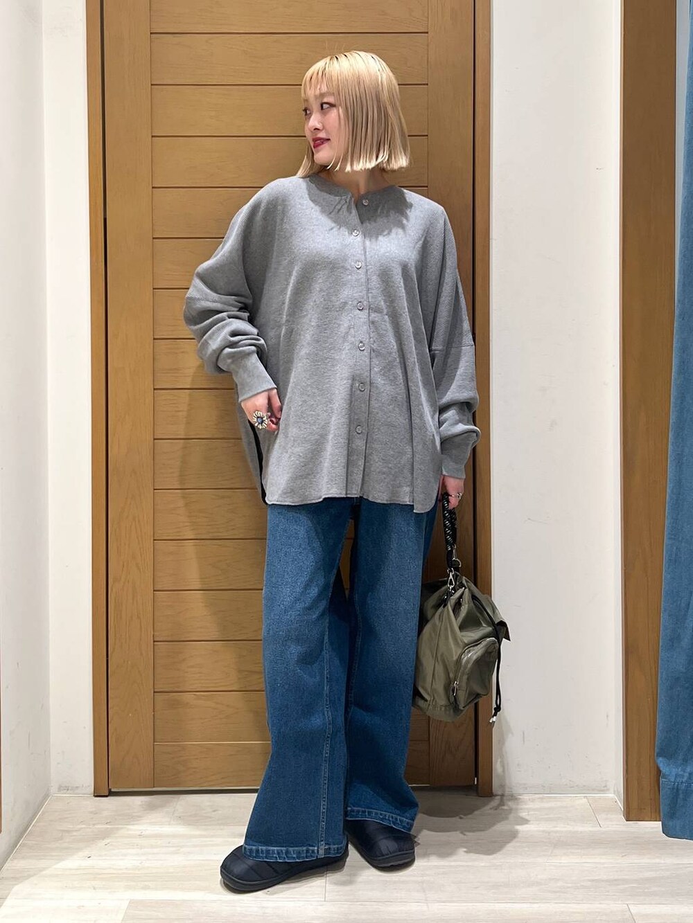 グリーン系のショルダーバッグ、グレー系のカーディガン/ボレロ、ブルー系のデニムパンツを着用したレディースの冬コーディネートの2枚目の写真