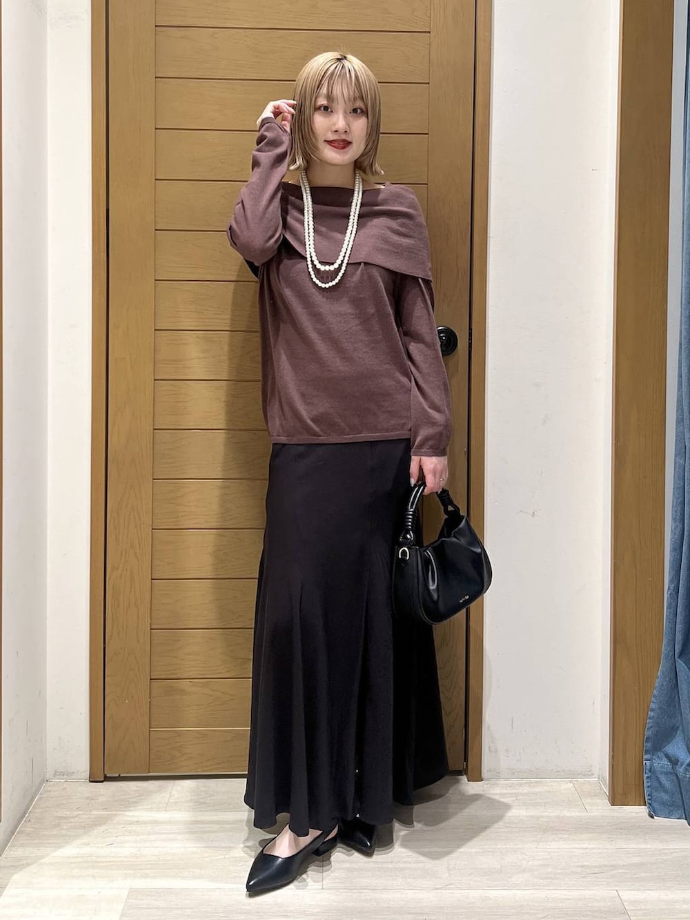 ブラック系のハンドバッグ、ブラック系のパンプス、ブラウン系のニット/セーターを着用したレディースの春コーディネートの3枚目の写真