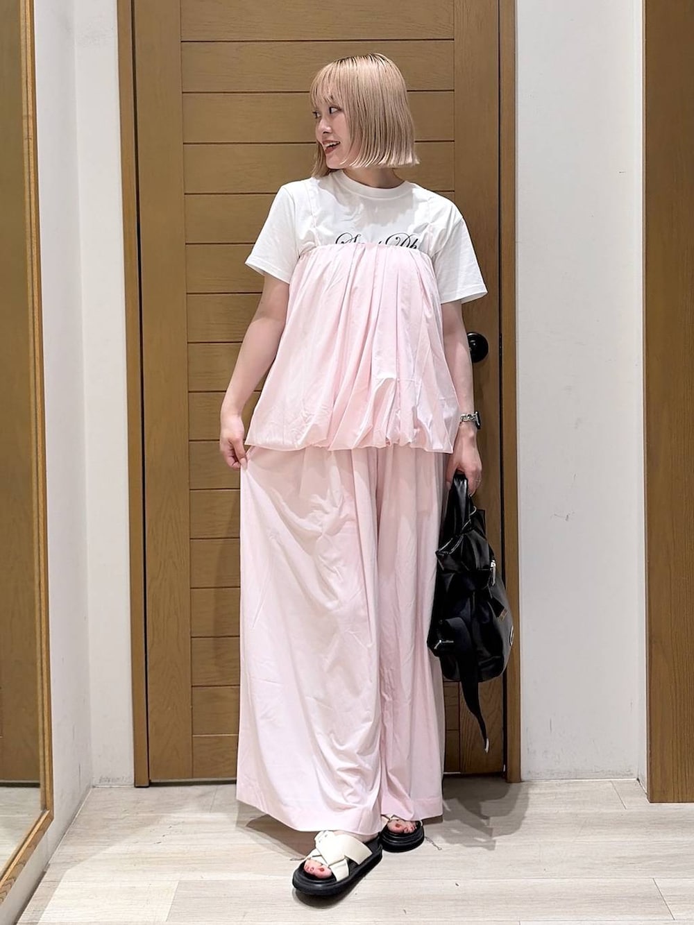ホワイト系のTシャツ/カットソー、ブラック系のトートバッグ、ホワイト系のサンダルを着用したレディースの夏コーディネートの3枚目の写真