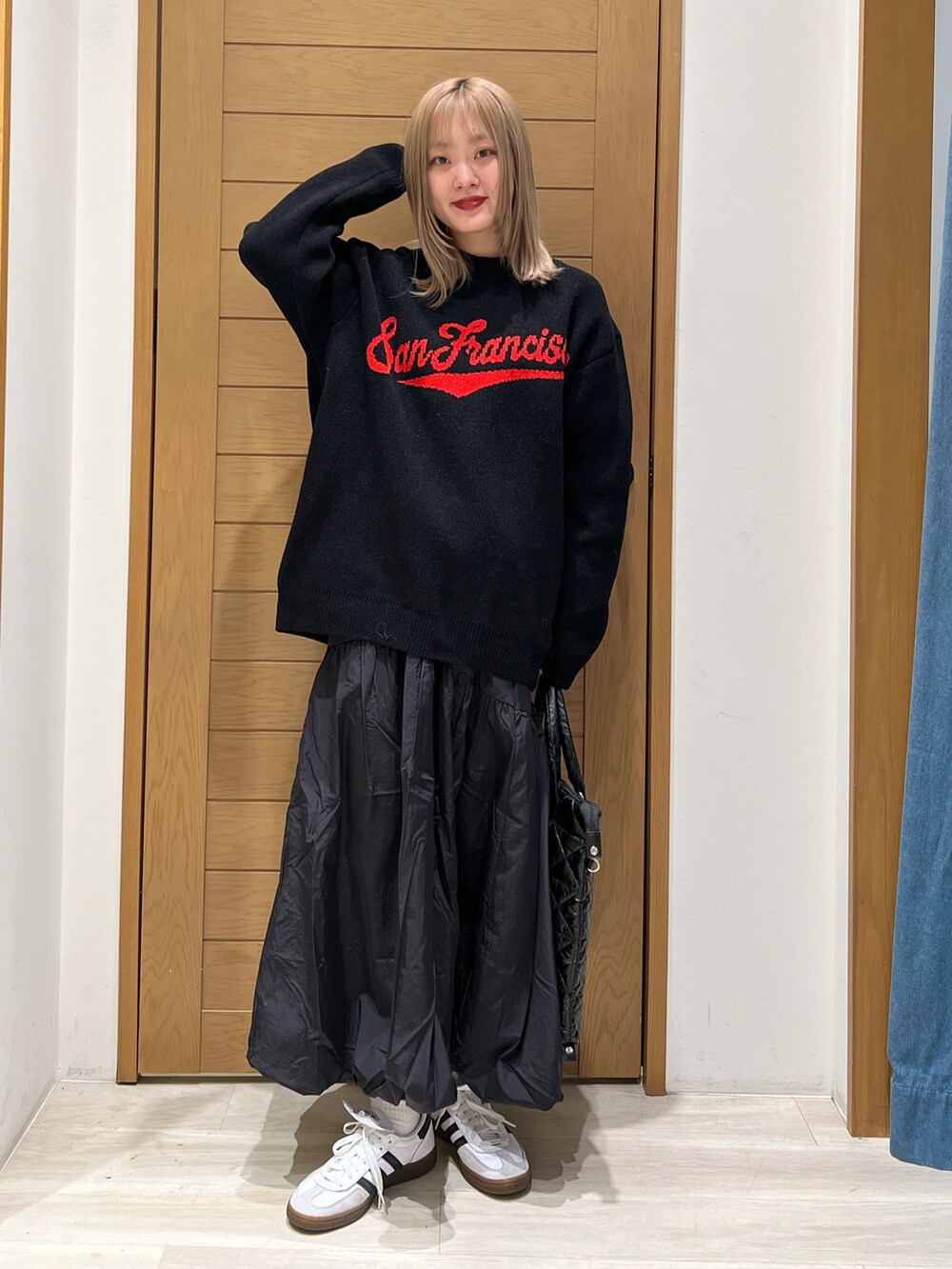 ブラック系のニット/セーター、ブラック系のスカート、ブラック系のトートバッグを着用したレディースの冬コーディネートの2枚目の写真