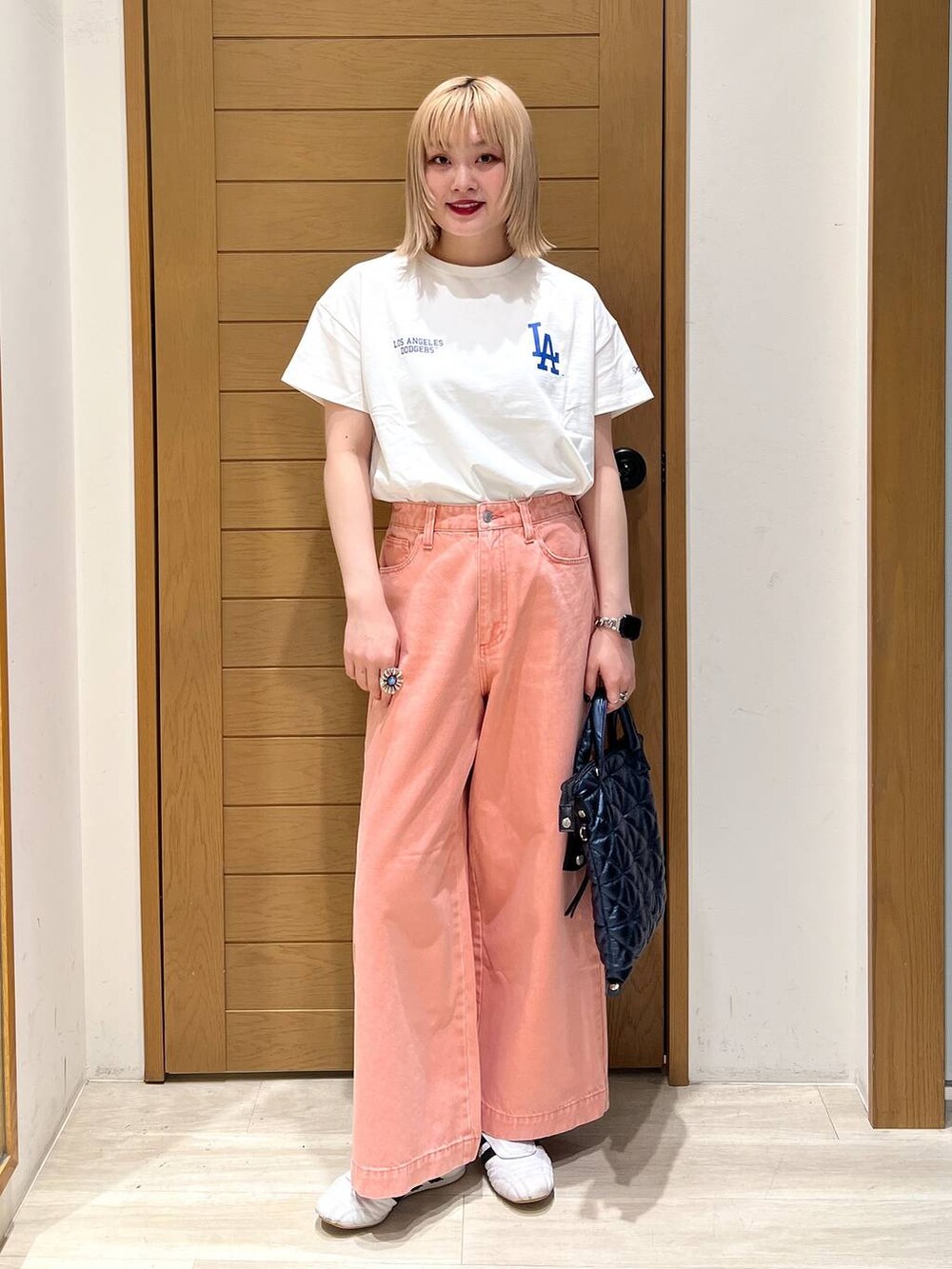 ピンク系のデニムパンツ、ブルー系のハンドバッグ、ホワイト系のTシャツ/カットソーを着用したレディースの春コーディネートの4枚目の写真