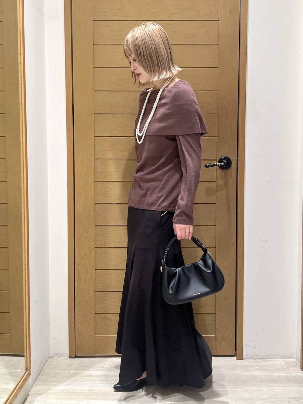 ブラック系のハンドバッグ、ブラック系のパンプス、ブラウン系のニット/セーターを着用したレディースの春コーディネートの4枚目の写真