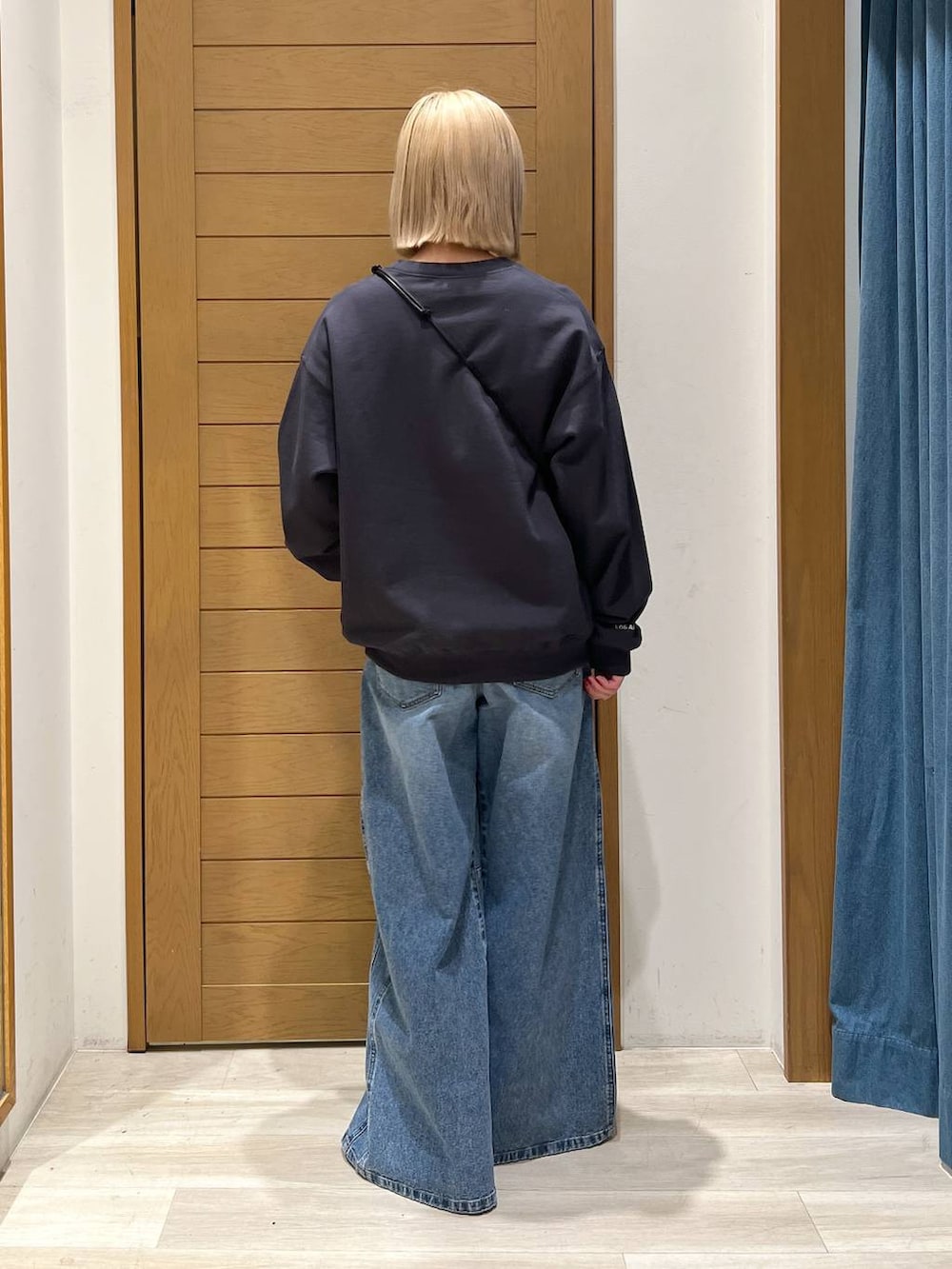 グレー系のショルダーバッグ、ブルー系のデニムパンツ、グレー系のスウェットを着用したレディースの冬コーディネートの4枚目の写真