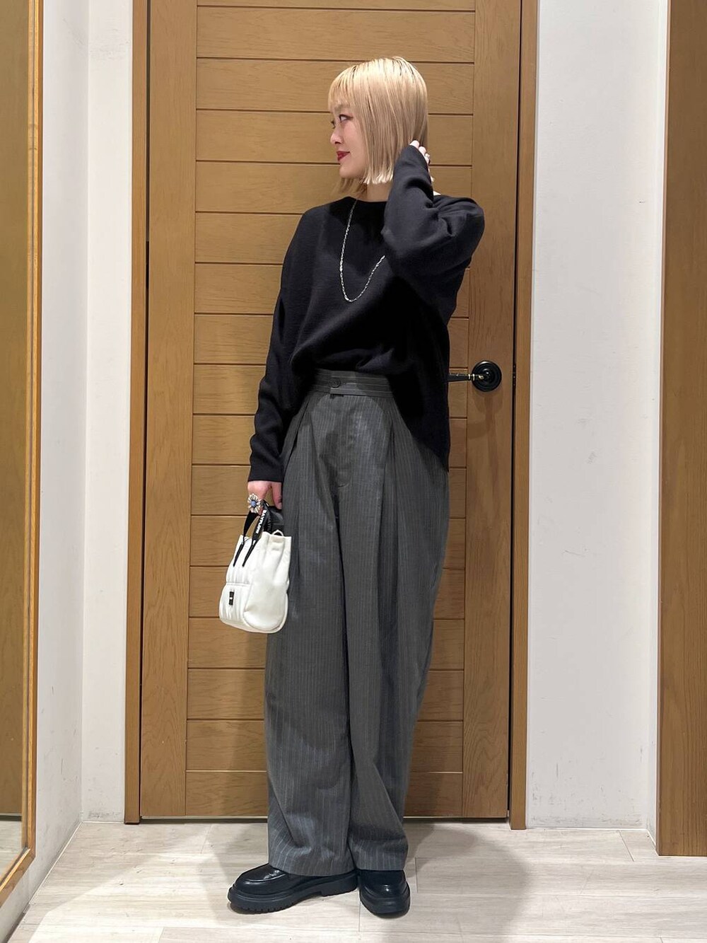 ブラック系のニット/セーター、その他のローファー、ベージュ系のショルダーバッグを着用したレディースの冬コーディネートの2枚目の写真