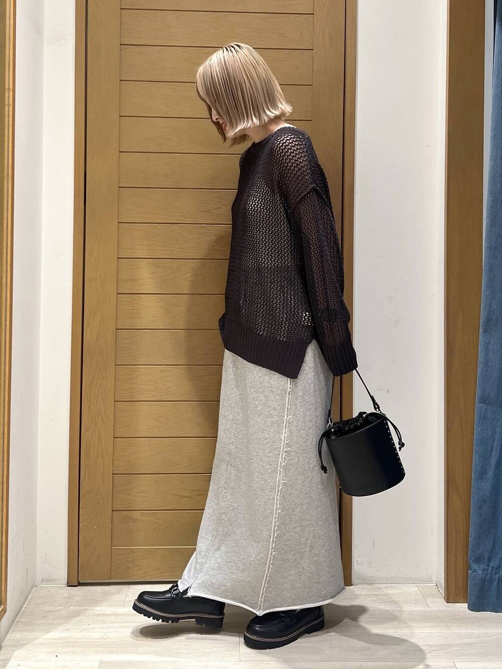 ブラック系のハンドバッグ、グレー系のスカート、ブラック系のローファーを着用したレディースの春コーディネートの4枚目の写真