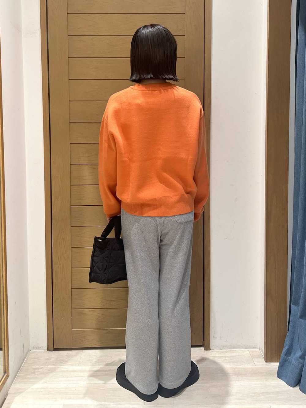 ブラック系のショルダーバッグ、オレンジ系のニット/セーター、グレー系のその他パンツを着用したレディースの秋コーディネートの4枚目の写真