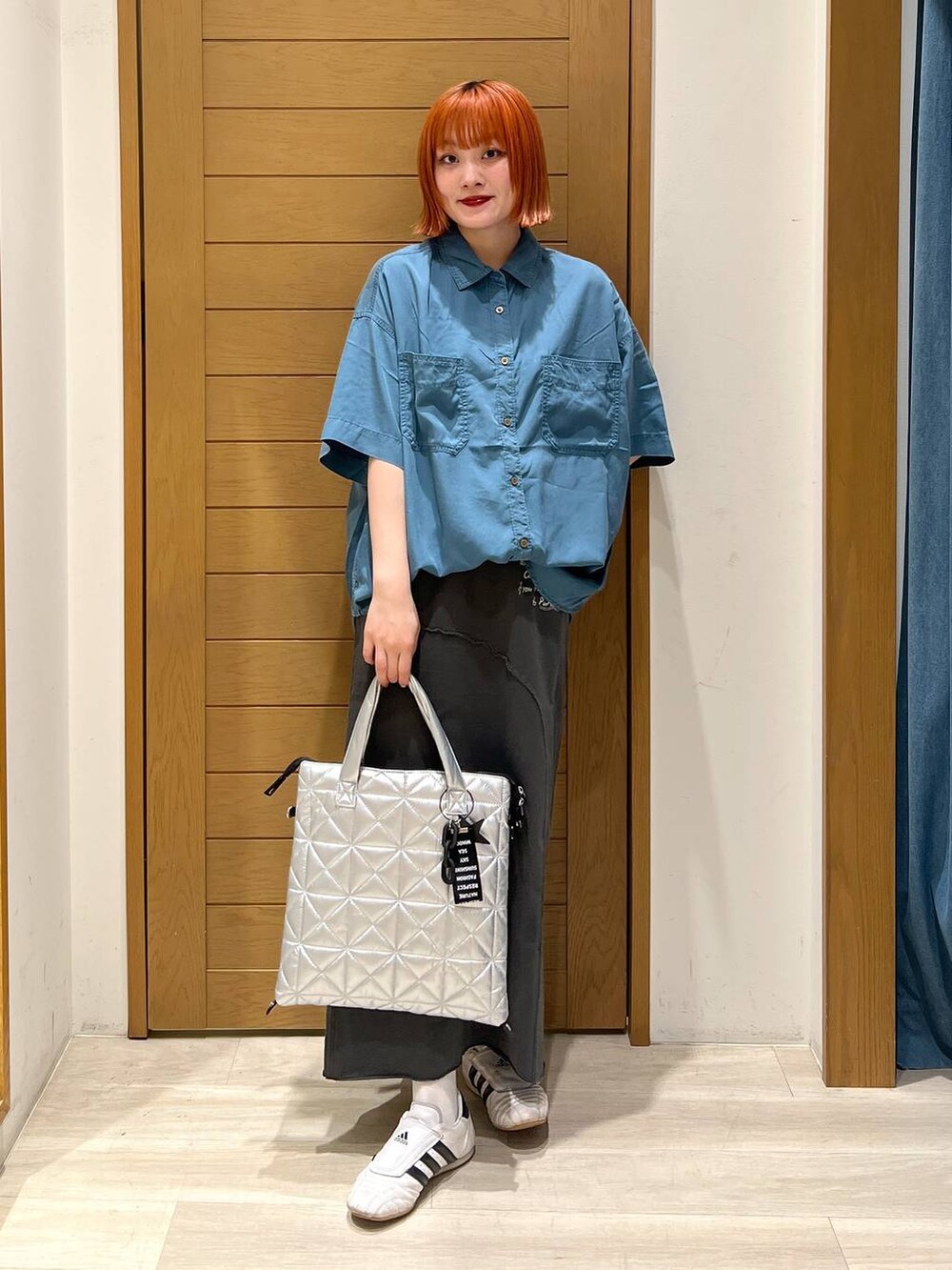 ブルー系のシャツ/ブラウス、グレー系のスカート、シルバー系のトートバッグを着用したレディースの夏コーディネートの2枚目の写真