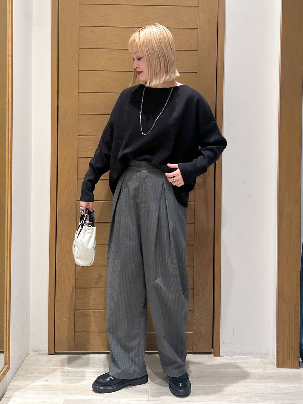 ブラック系のニット/セーター、その他のローファー、ベージュ系のショルダーバッグを着用したレディースの冬コーディネートの3枚目の写真