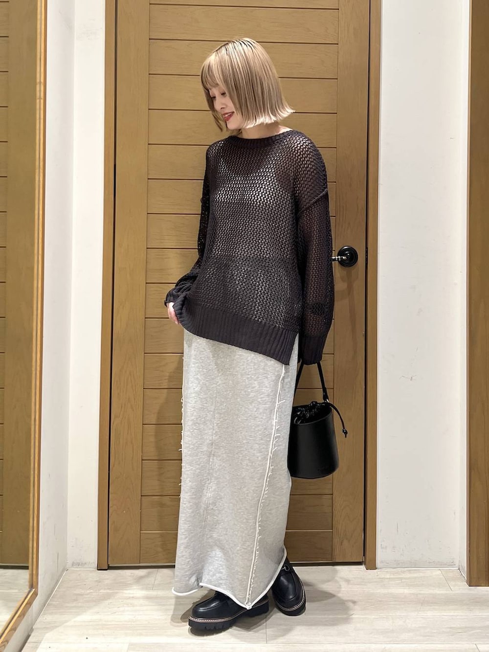 ブラック系のハンドバッグ、グレー系のスカート、ブラック系のローファーを着用したレディースの春コーディネートの3枚目の写真