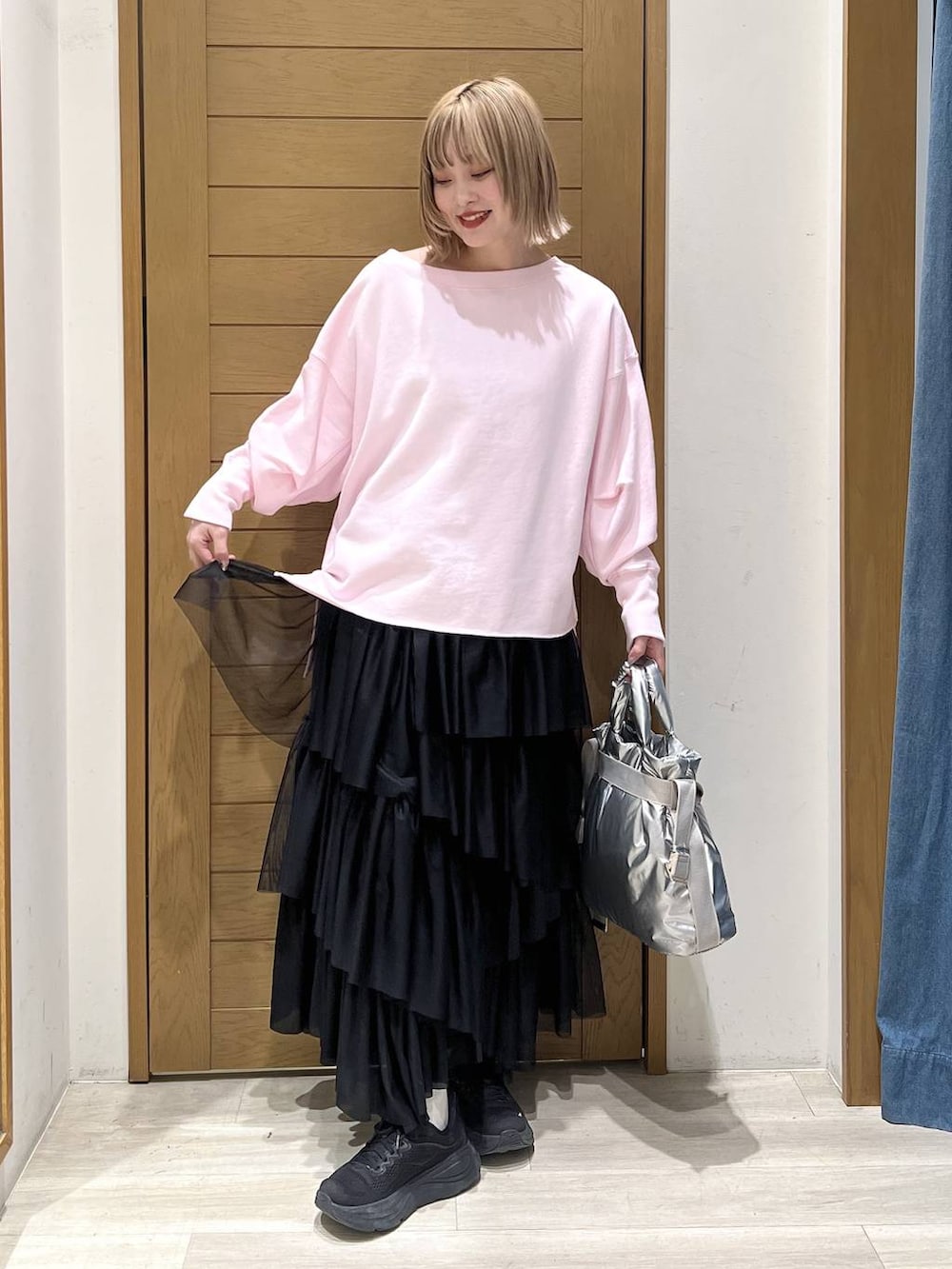 シルバー系のトートバッグ、ピンク系のスウェット、ブラック系のスカートを着用したレディースの春コーディネートの3枚目の写真