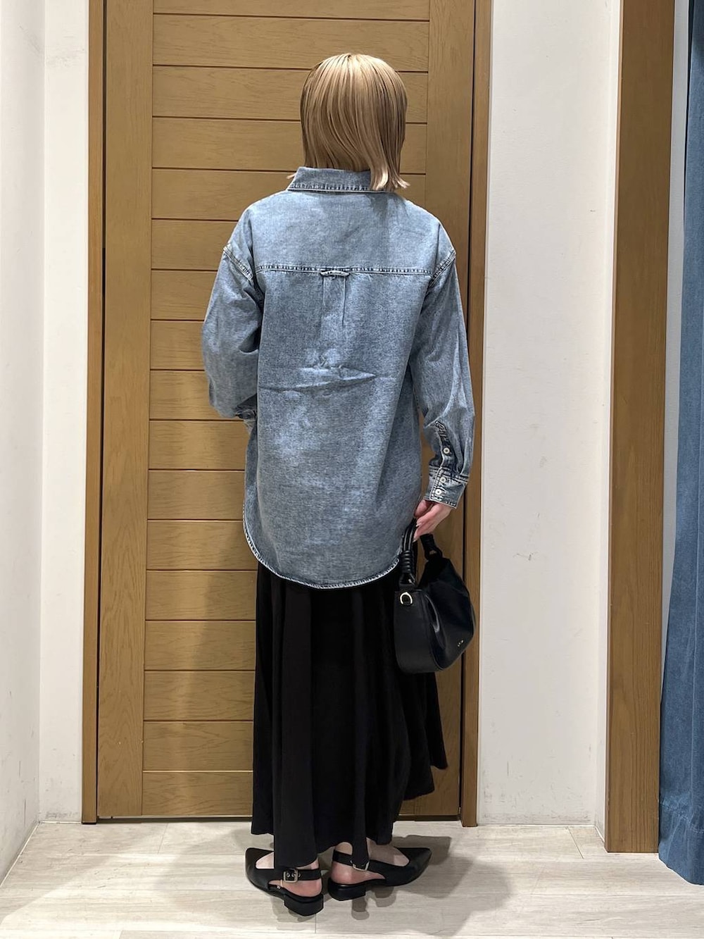 ブラック系のハンドバッグ、ブラック系のパンプス、ブルー系のシャツ/ブラウスを着用したレディースの春コーディネートの4枚目の写真