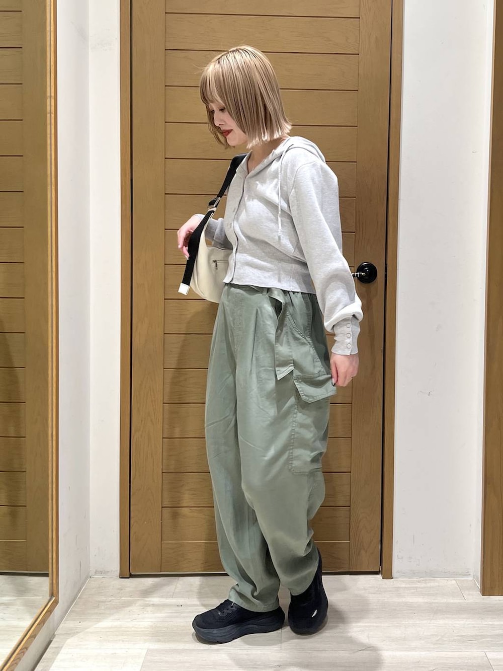 グリーン系のカーゴパンツ、ホワイト系のショルダーバッグ、グレー系のパーカーを着用したレディースの春コーディネートの3枚目の写真