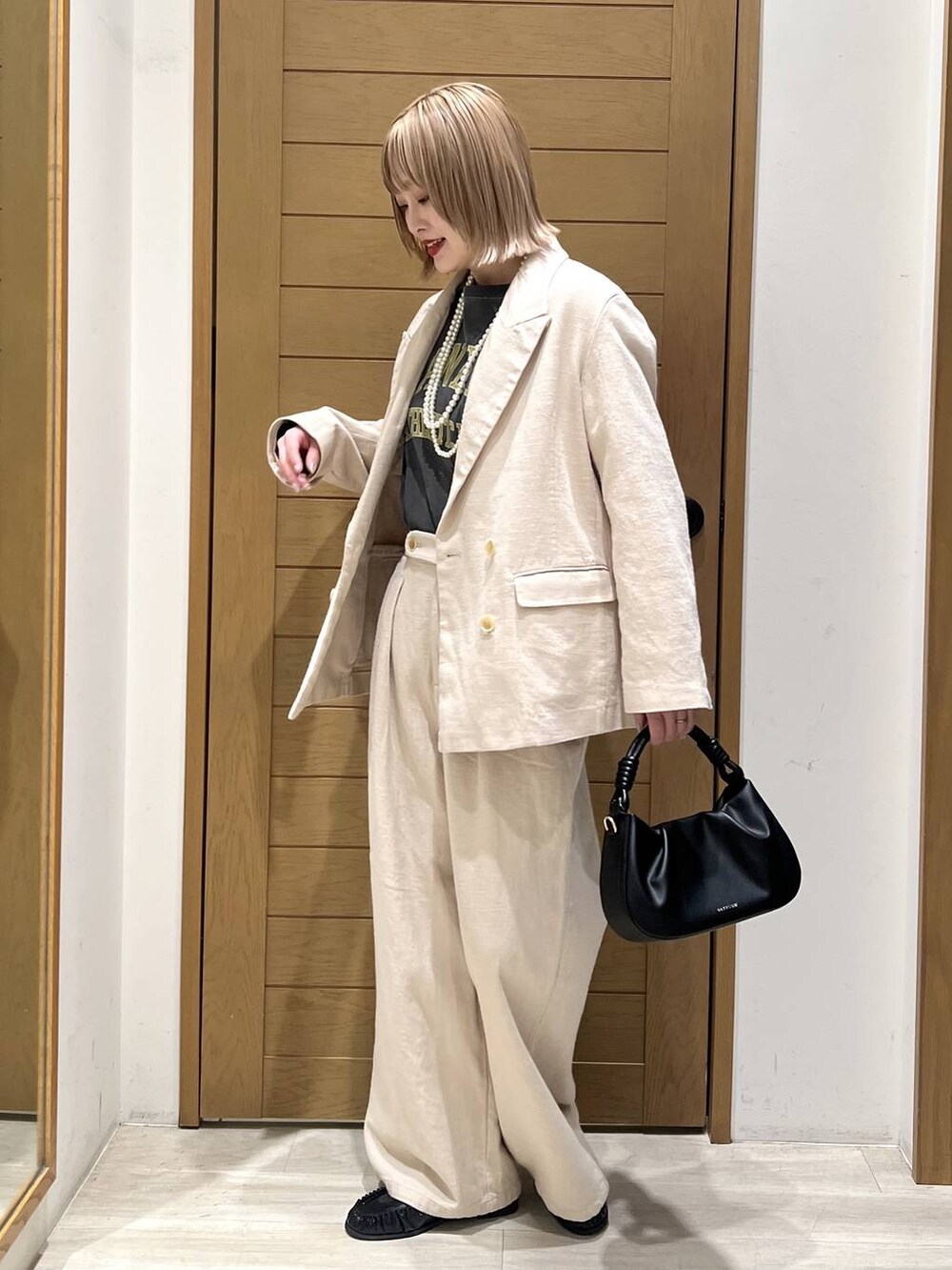 レッド系のTシャツ/カットソー、ブラック系のハンドバッグ、ブラック系のローファーを着用したレディースの春コーディネートの3枚目の写真