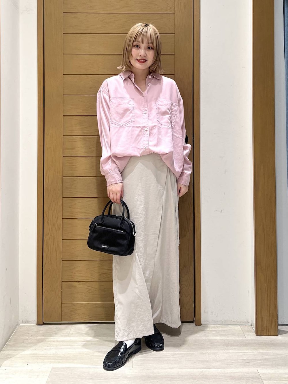 ピンク系のシャツ/ブラウス、ブラック系のハンドバッグ、ブラック系のローファーを着用したレディースの春コーディネートの2枚目の写真
