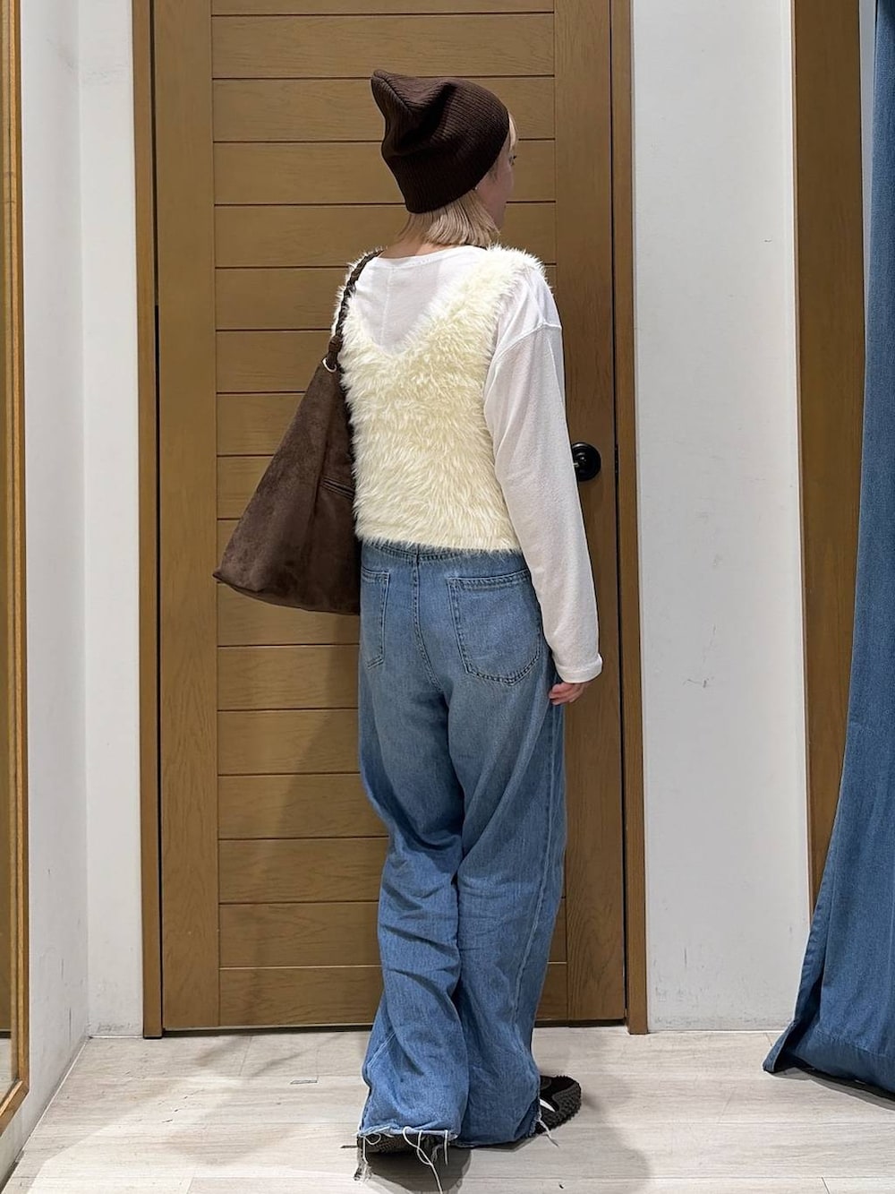ブルー系のデニムパンツ、ホワイト系のベスト、ブラウン系のトートバッグを着用したレディースの夏コーディネートの3枚目の写真