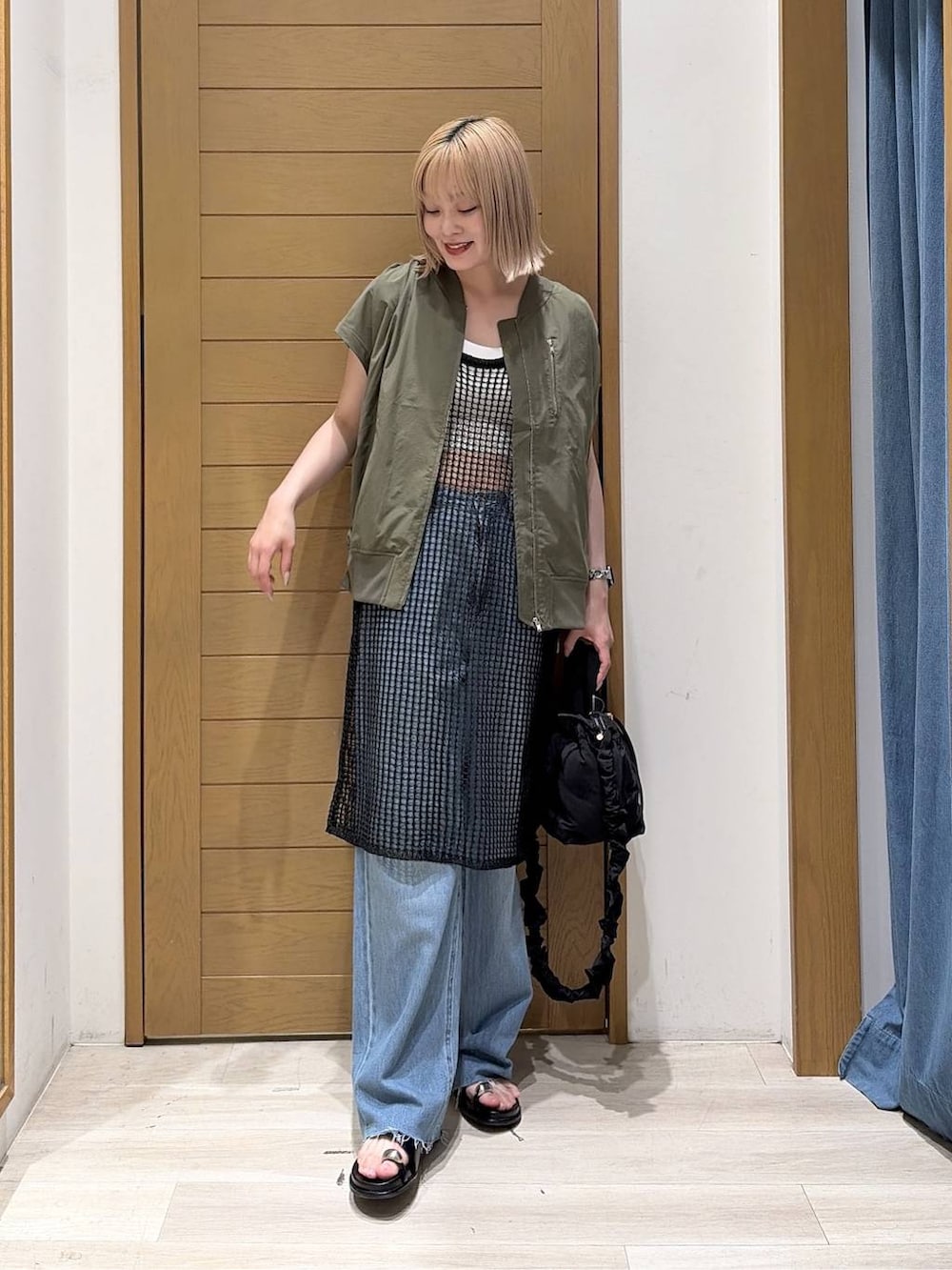 ブルー系のデニムパンツ、グリーン系のブルゾン、ブラック系のショルダーバッグを着用したレディースの夏コーディネートの2枚目の写真