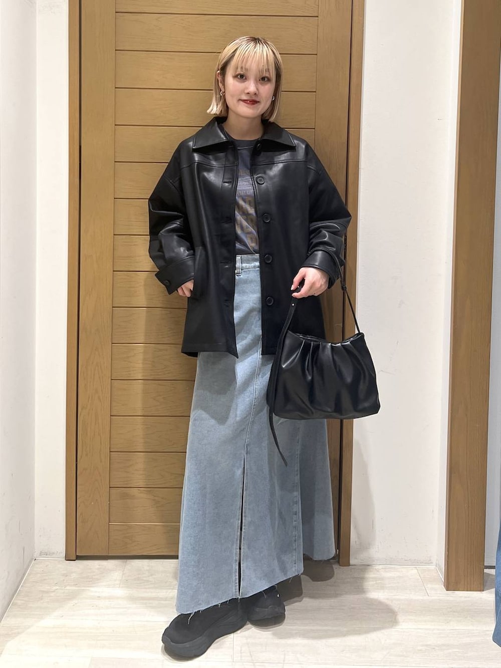 ブラック系のハンドバッグ、ブラック系のブルゾン、ブルー系のスカートを着用したレディースの秋コーディネートの2枚目の写真