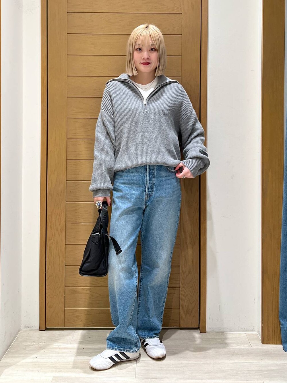 ブルー系のデニムパンツ、ブラック系のトートバッグ、グレー系のニット/セーターを着用したレディースの冬コーディネートの2枚目の写真