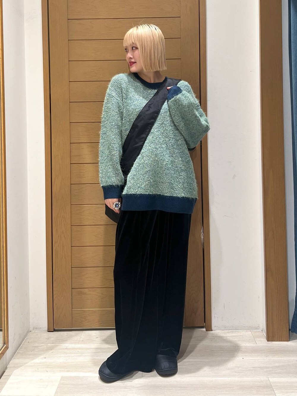 グリーン系のニット/セーター、ブラック系のショルダーバッグ、ブラック系のその他パンツを着用したレディースの冬コーディネートの2枚目の写真