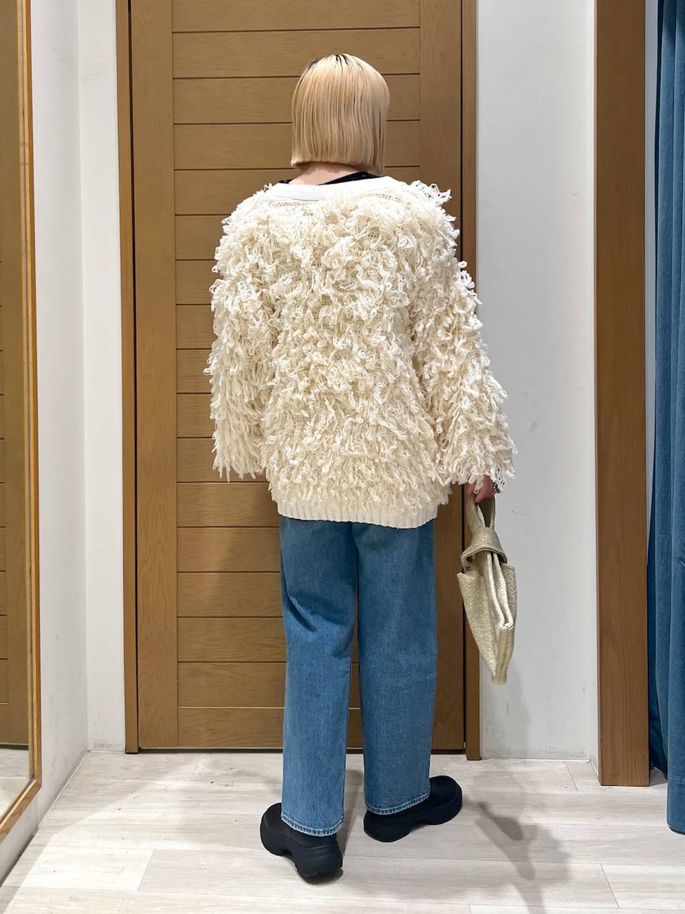 ブルー系のデニムパンツ、ホワイト系のカーディガン/ボレロ、イエロー系のハンドバッグを着用したレディースの冬コーディネートの4枚目の写真