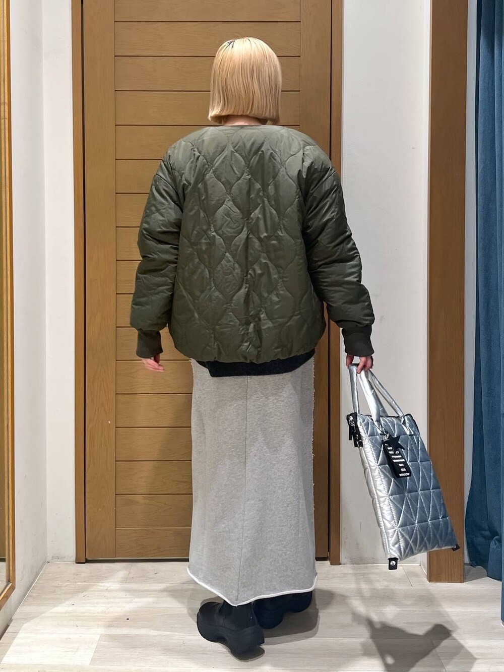 グリーン系のブルゾン、ブラック系のブーツ、シルバー系のトートバッグを着用したレディースの冬コーディネートの5枚目の写真