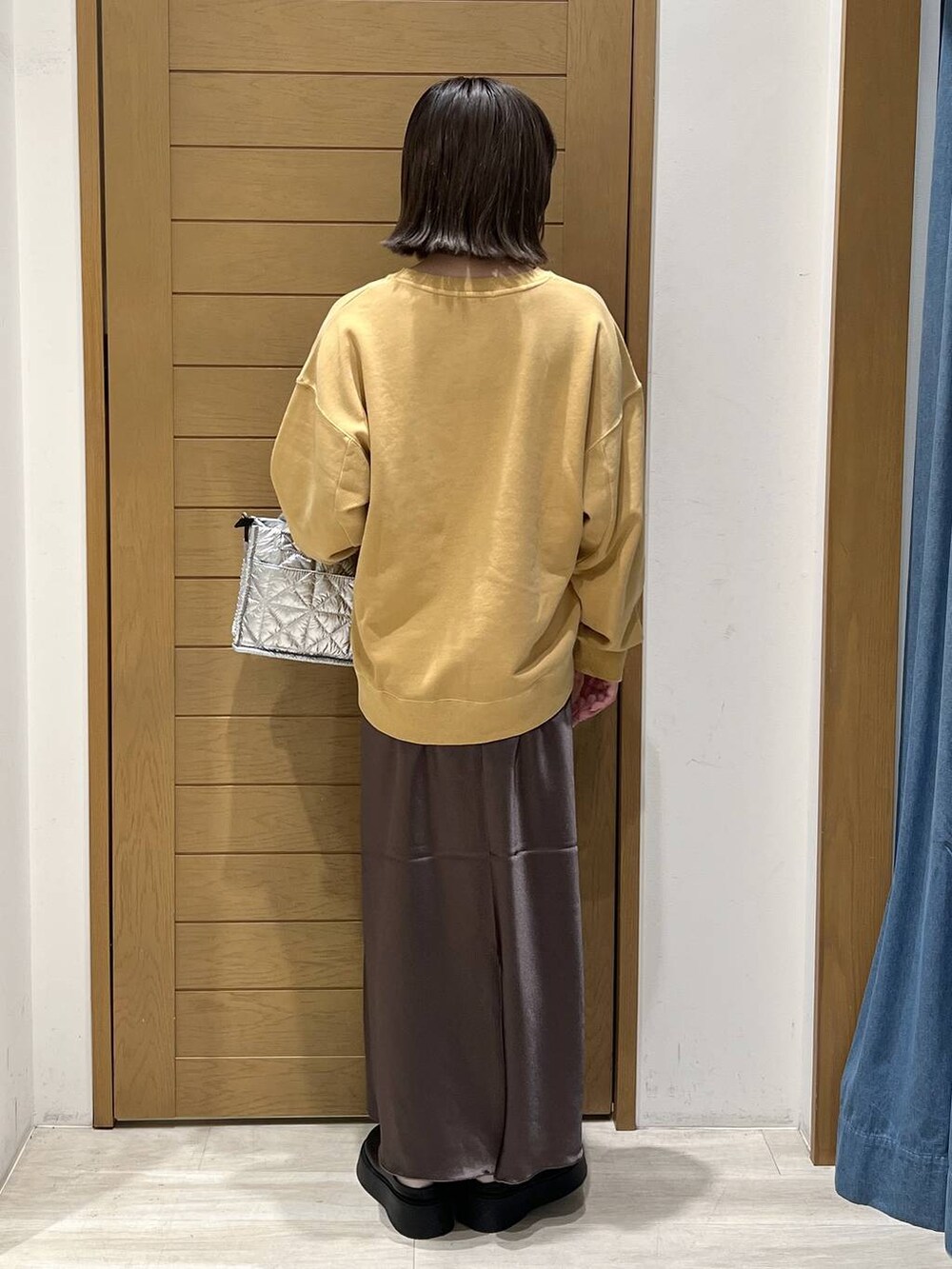 シルバー系のショルダーバッグ、ブラック系のサンダル、イエロー系のスウェットを着用したレディースの秋コーディネートの4枚目の写真