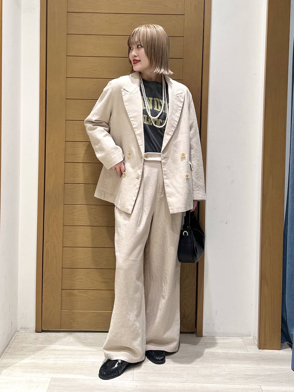 レッド系のTシャツ/カットソー、ブラック系のハンドバッグ、ブラック系のローファーを着用したレディースの春コーディネートの2枚目の写真