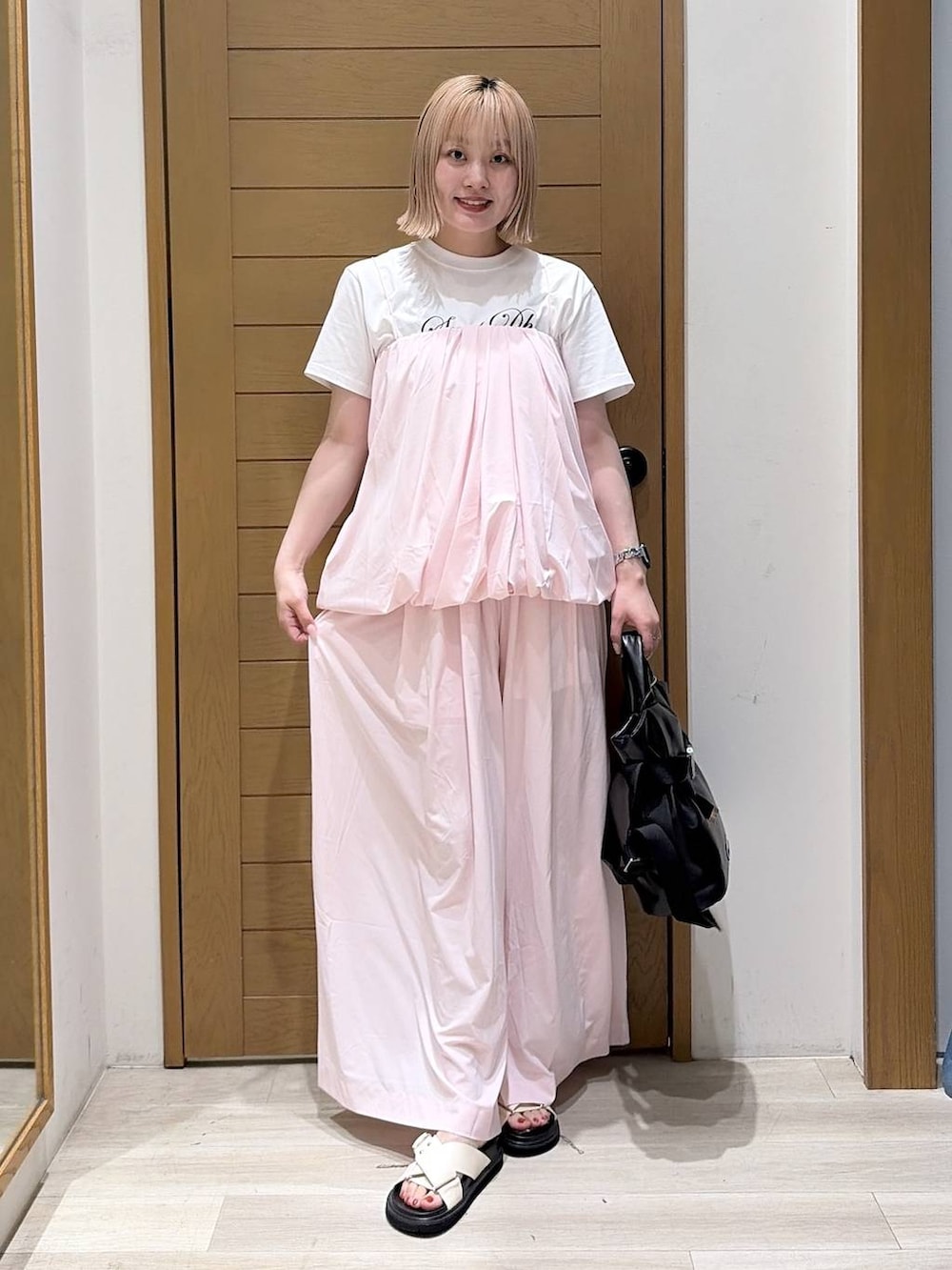 ホワイト系のTシャツ/カットソー、ブラック系のトートバッグ、ホワイト系のサンダルを着用したレディースの夏コーディネートの2枚目の写真