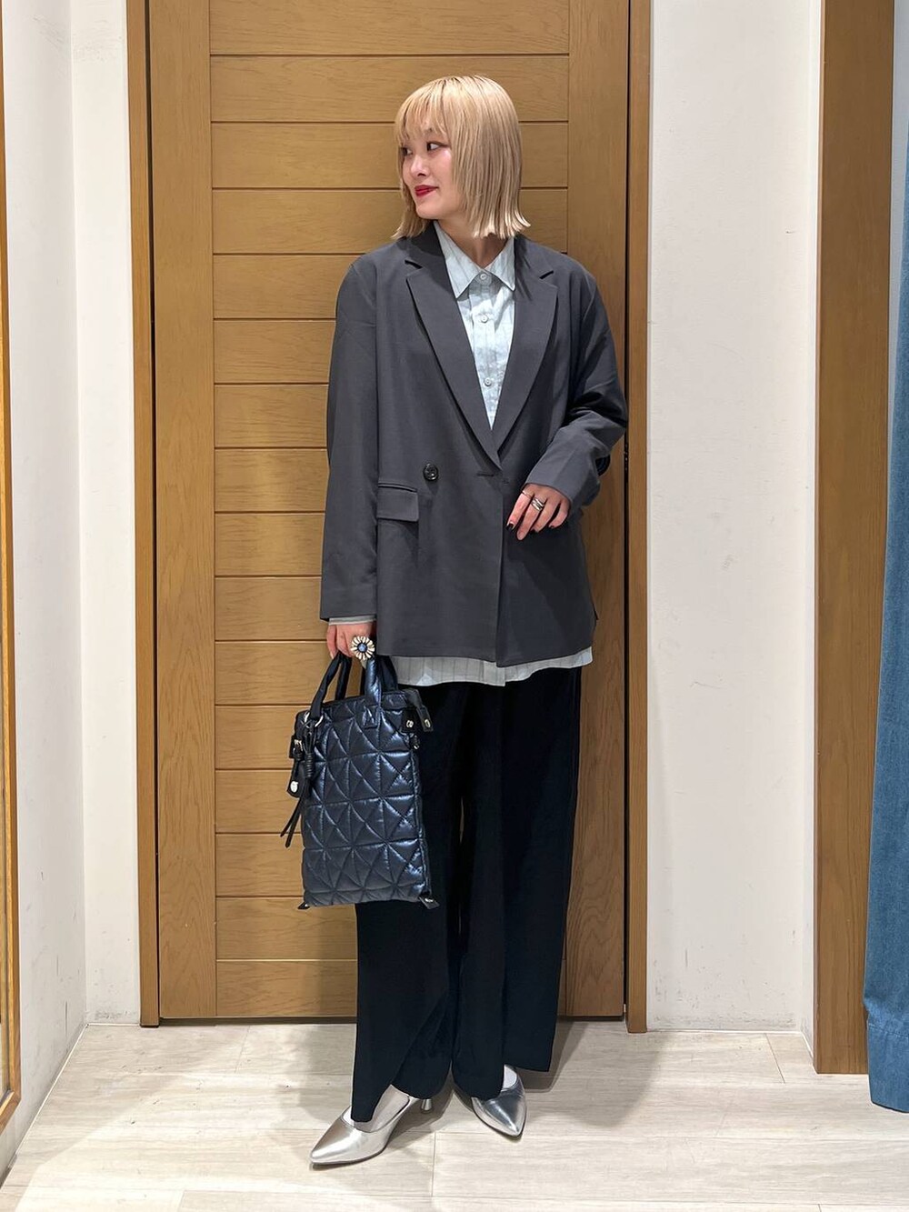 シルバー系のパンプス、ブラック系のその他パンツ、ブルー系のハンドバッグを着用したレディースの春コーディネートの2枚目の写真