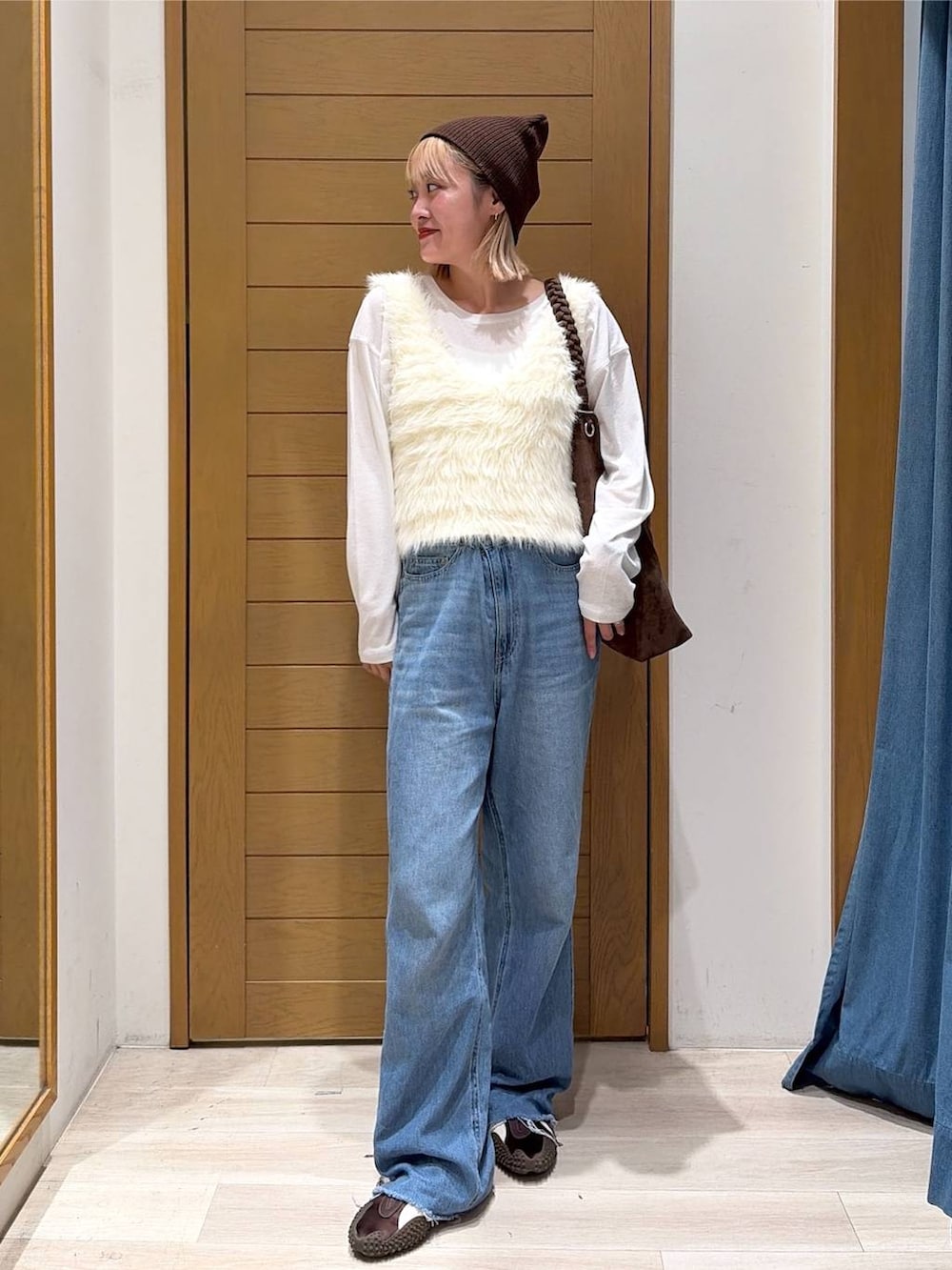 ブルー系のデニムパンツ、ホワイト系のベスト、ブラウン系のトートバッグを着用したレディースの夏コーディネートの2枚目の写真