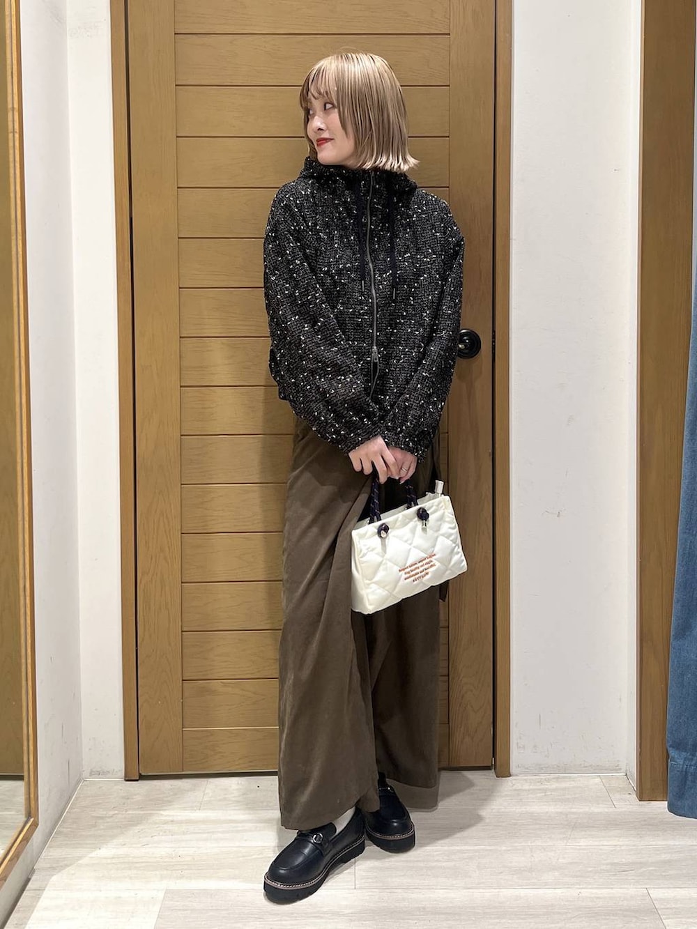 ブラック系のローファー、ブラック系のブルゾン、ホワイト系のショルダーバッグを着用したレディースの春コーディネートの2枚目の写真