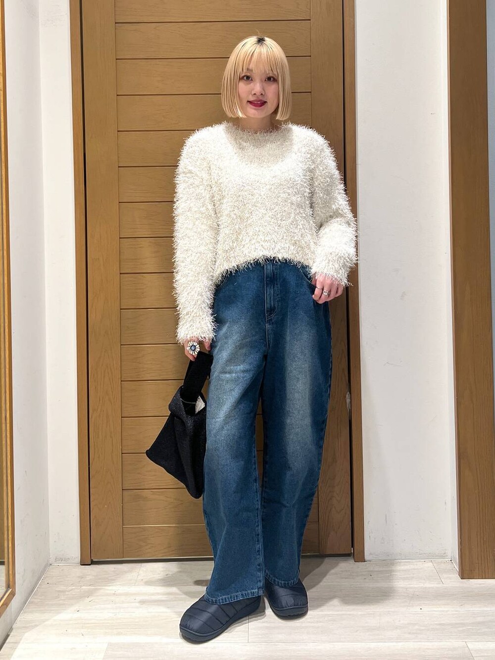 ホワイト系のニット/セーター、ブルー系のデニムパンツ、ブラック系のハンドバッグを着用したレディースの冬コーディネートの4枚目の写真