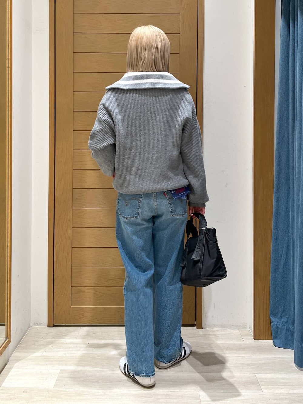 ブルー系のデニムパンツ、ブラック系のトートバッグ、グレー系のニット/セーターを着用したレディースの冬コーディネートの4枚目の写真