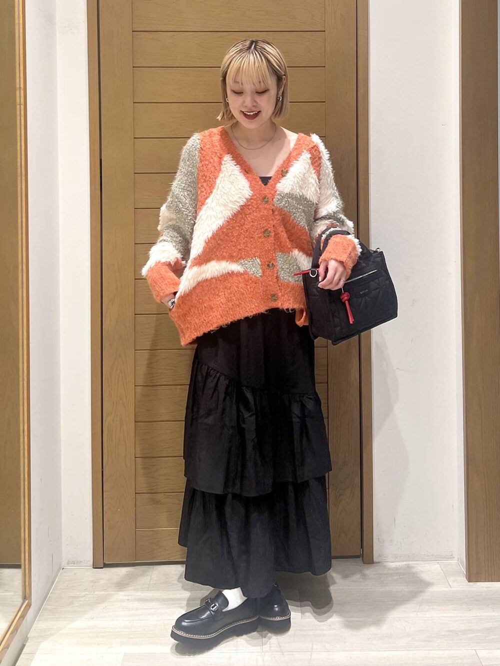 ブラック系のショルダーバッグ、ブラック系のローファー、ブラック系のスカートを着用したレディースの秋コーディネートの3枚目の写真