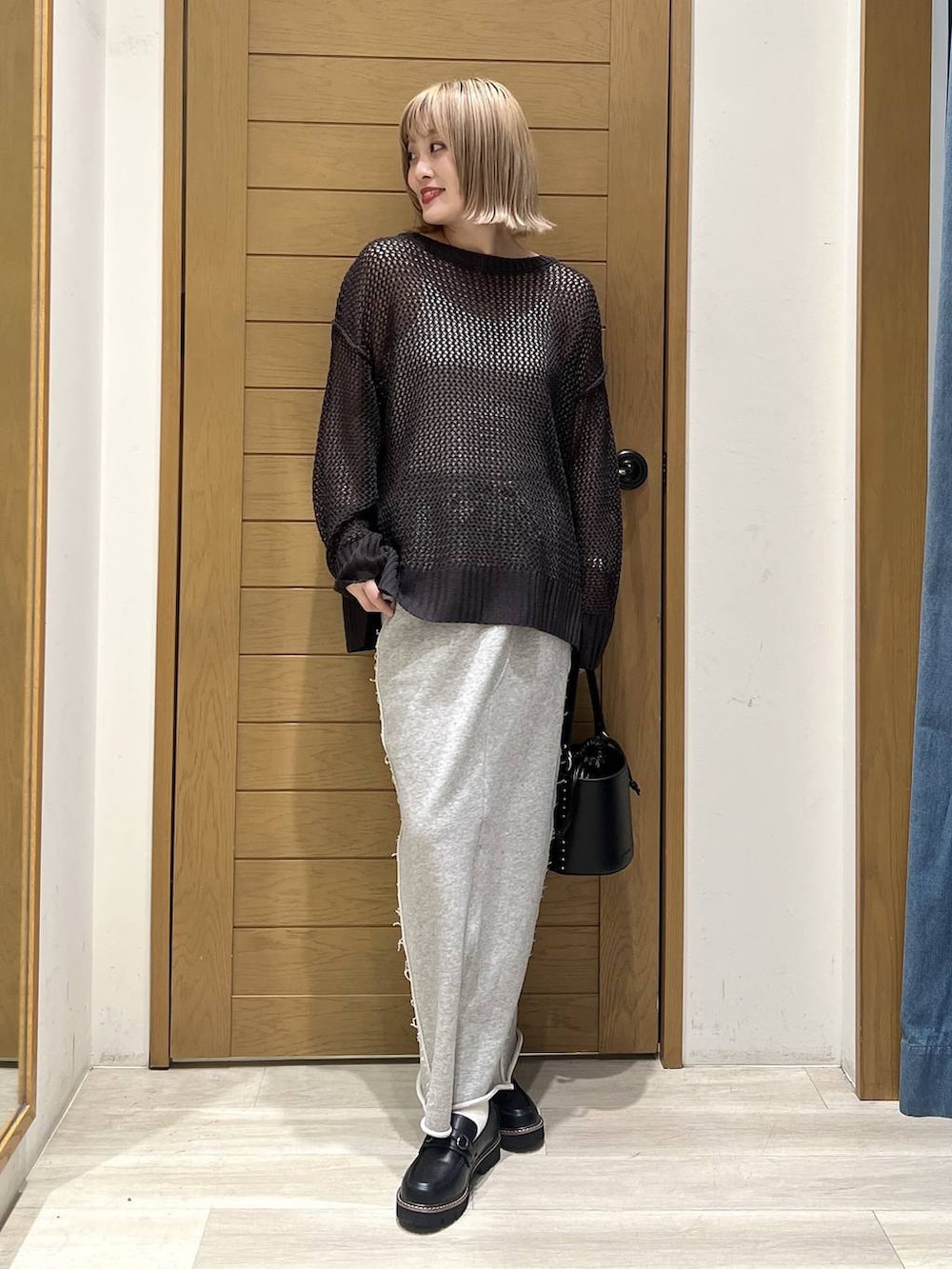 ブラック系のハンドバッグ、グレー系のスカート、ブラック系のローファーを着用したレディースの春コーディネートの2枚目の写真