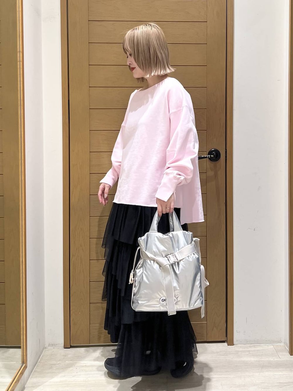 シルバー系のトートバッグ、ピンク系のスウェット、ブラック系のスカートを着用したレディースの春コーディネートの5枚目の写真