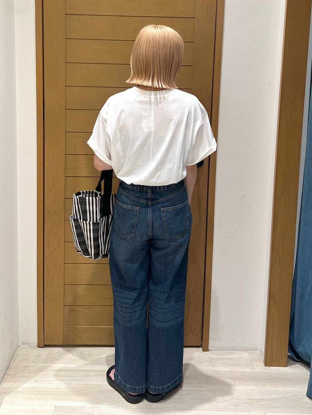 ブルー系のデニムパンツ、オレンジ系のTシャツ/カットソー、ブラック系のサンダルを着用したレディースの夏コーディネートの2枚目の写真