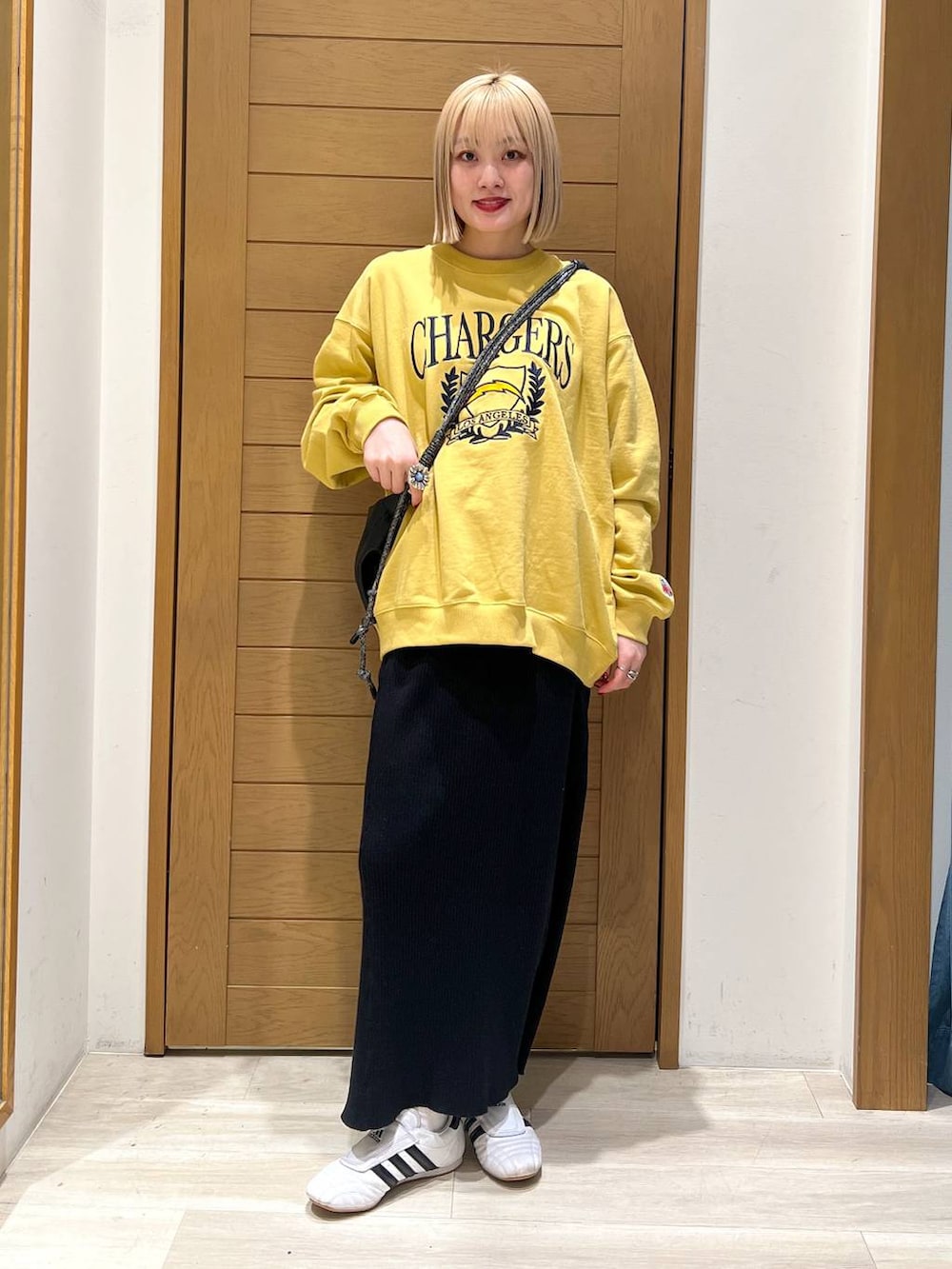 ブラック系のスカート、ブラック系のショルダーバッグ、イエロー系のスウェットを着用したレディースの冬コーディネートの4枚目の写真