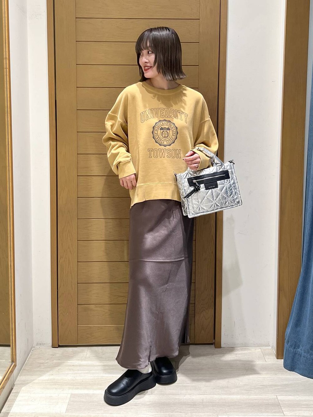 シルバー系のショルダーバッグ、ブラック系のサンダル、イエロー系のスウェットを着用したレディースの秋コーディネートの2枚目の写真