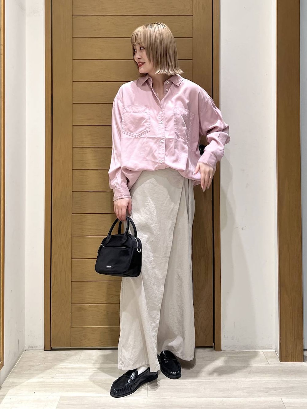 ピンク系のシャツ/ブラウス、ブラック系のハンドバッグ、ブラック系のローファーを着用したレディースの春コーディネートの3枚目の写真