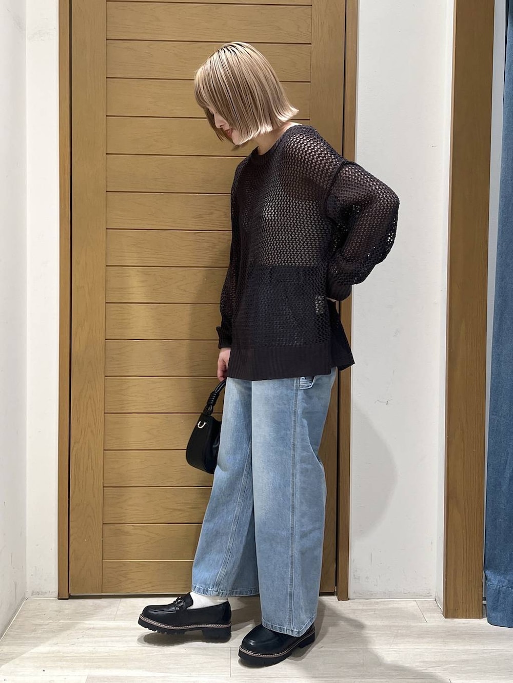 ブルー系のデニムパンツ、ブラック系のハンドバッグ、ブラック系のローファーを着用したレディースの春コーディネートの2枚目の写真