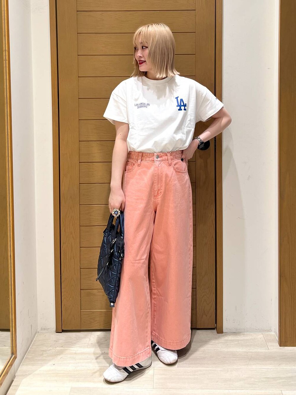 ピンク系のデニムパンツ、ブルー系のハンドバッグ、ホワイト系のTシャツ/カットソーを着用したレディースの春コーディネートの2枚目の写真