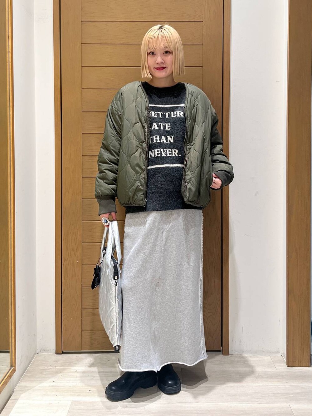 グリーン系のブルゾン、ブラック系のブーツ、シルバー系のトートバッグを着用したレディースの冬コーディネートの6枚目の写真