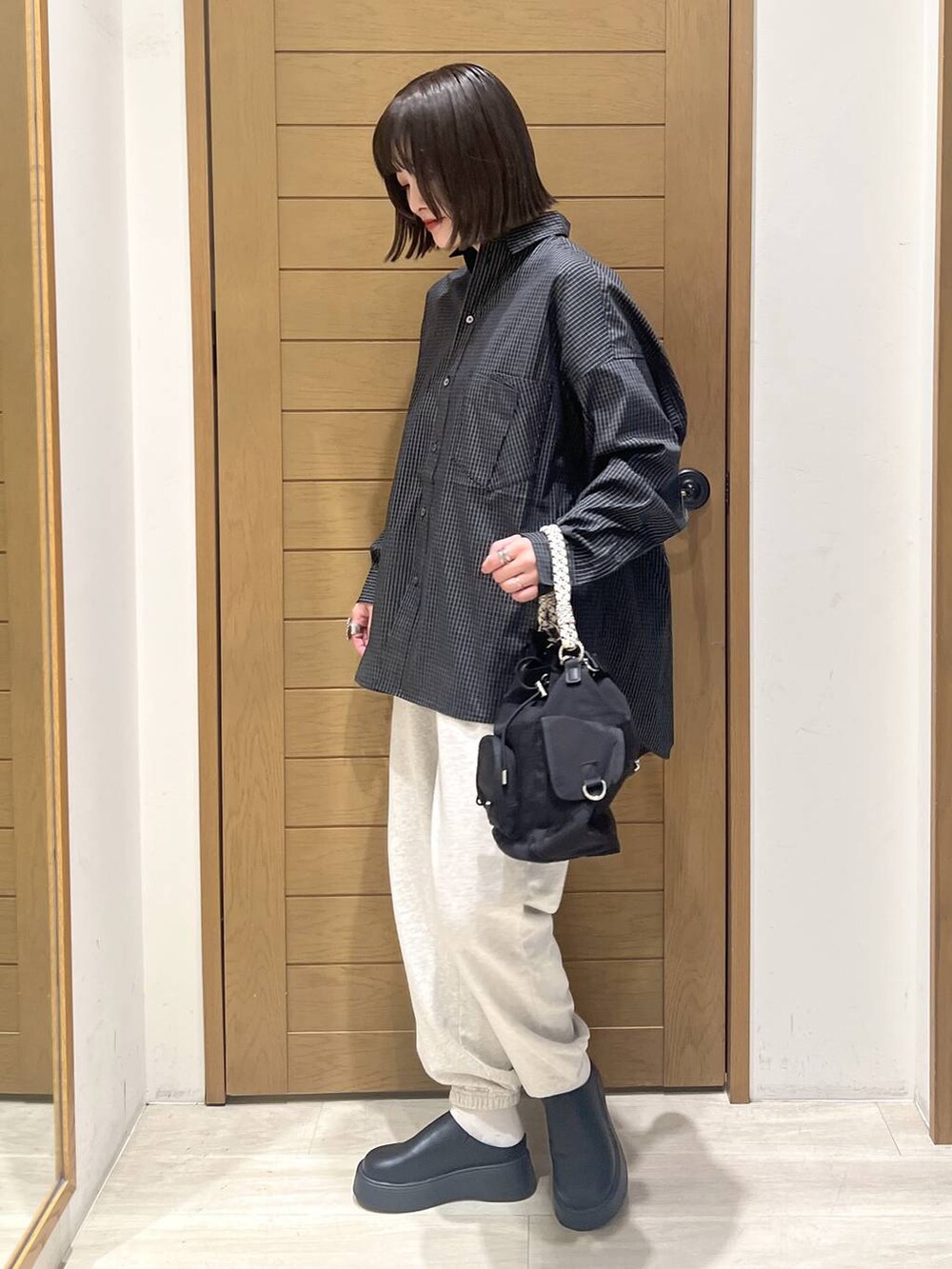 ベージュ系のスウェットパンツ、ブラック系のサンダル、ブラック系のハンドバッグを着用したレディースの秋コーディネートの3枚目の写真