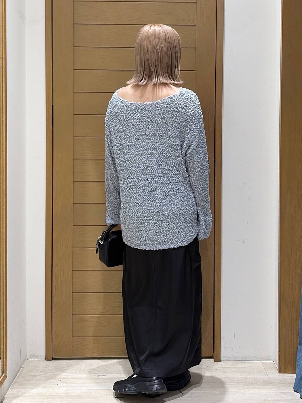 ブラック系のスニーカー、ブルー系のニット/セーター、ブラック系のハンドバッグを着用したレディースの秋コーディネートの4枚目の写真