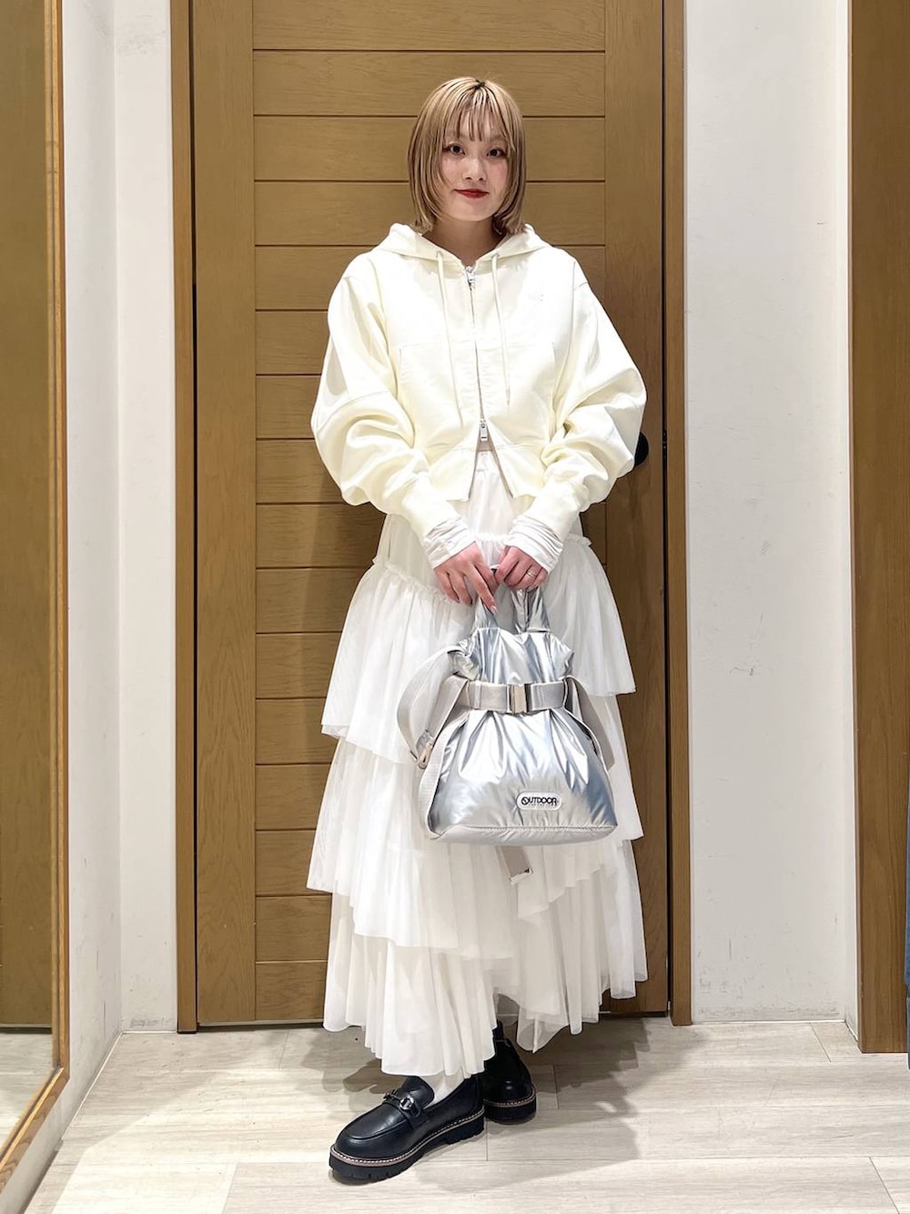 シルバー系のトートバッグ、ブラック系のローファー、ホワイト系のTシャツ/カットソーを着用したレディースの春コーディネートの6枚目の写真