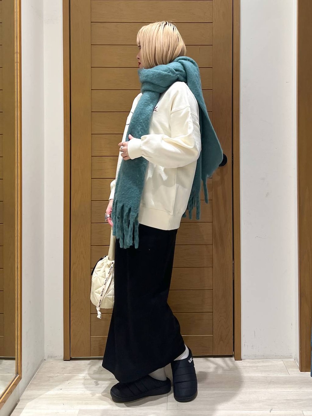 ベージュ系のショルダーバッグ、ホワイト系のスウェット、ブラック系のスカートを着用したレディースの冬コーディネートの3枚目の写真