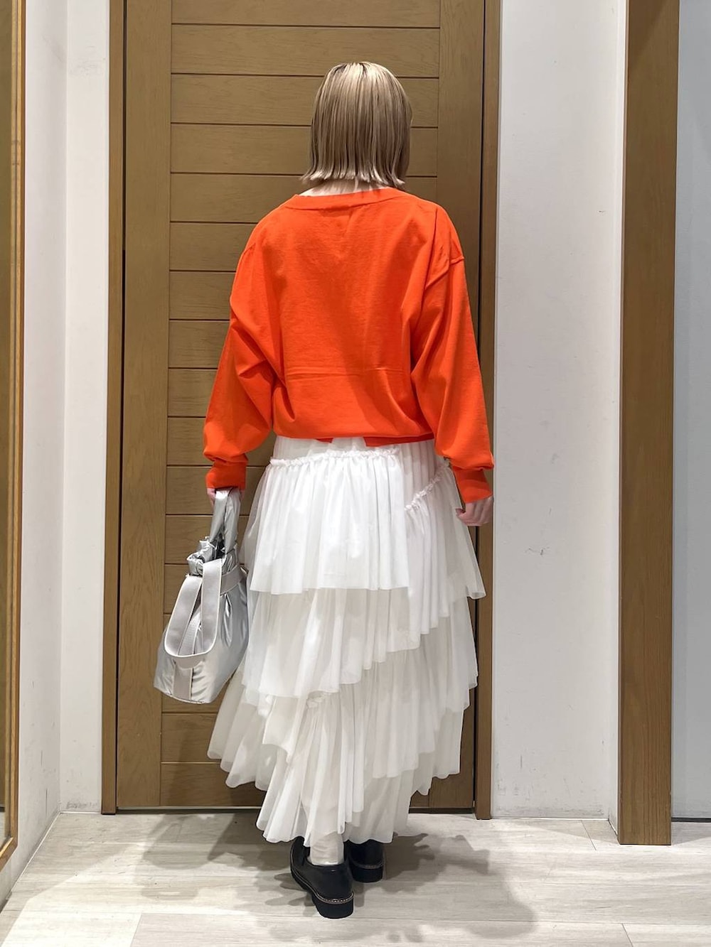 シルバー系のトートバッグ、ブラック系のローファー、オレンジ系のニット/セーターを着用したレディースの春コーディネートの4枚目の写真