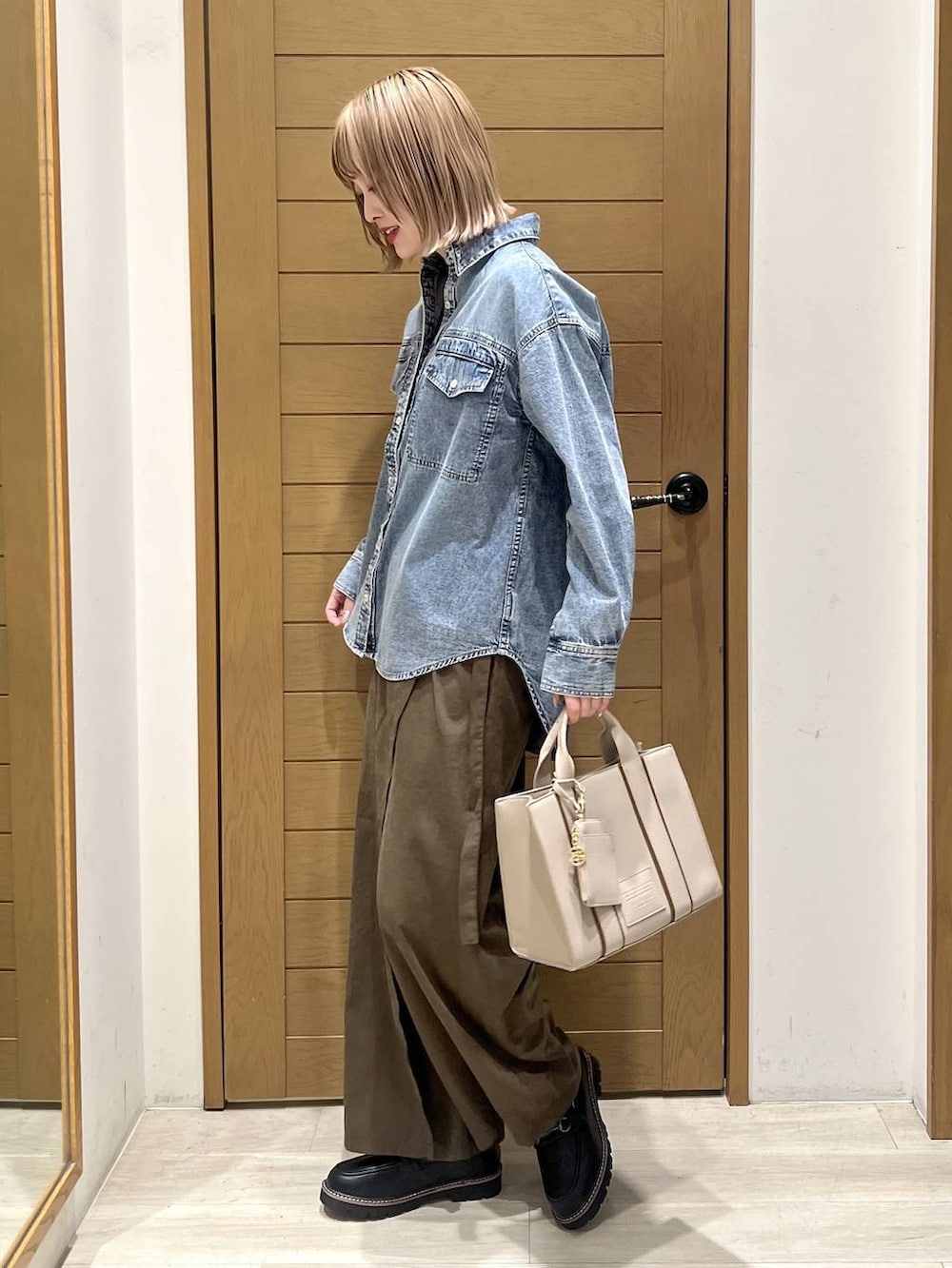 ブラック系のローファー、ベージュ系のハンドバッグ、ブルー系のシャツ/ブラウスを着用したレディースの春コーディネートの3枚目の写真