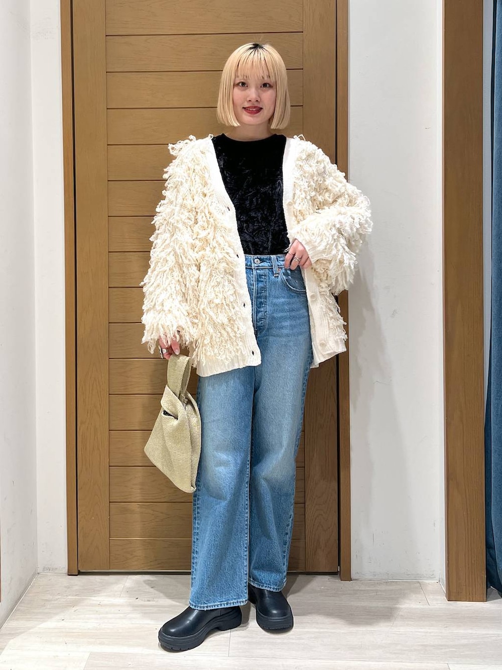 ブルー系のデニムパンツ、ホワイト系のカーディガン/ボレロ、イエロー系のハンドバッグを着用したレディースの冬コーディネートの7枚目の写真